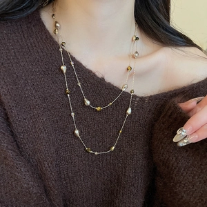 Detail of 18k gold-plated layered necklace with tiger eye beads and pearls on a model
