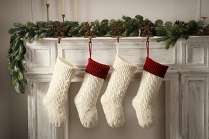 Close-up of white knitted Christmas stockings with cable pattern hanging on fireplace