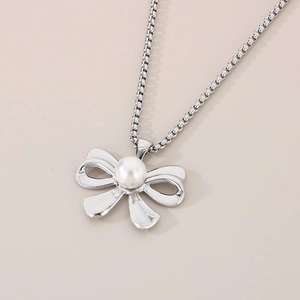 Detailed view of silver bow pendant with white pearl inlay on a round box chain