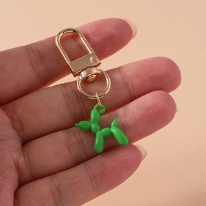 Close-up of green shiny balloon dog keychain with golden metal clasp held by hand