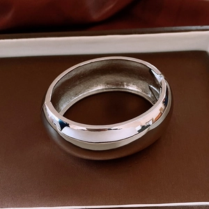 Detailed macro view of silver-tone metal cuff bracelet with polished finish and hinge opening
