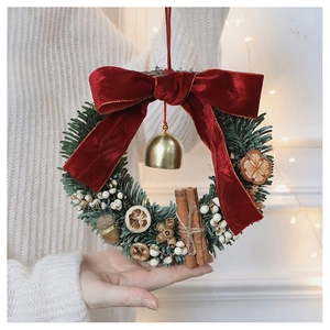 Handheld artificial Christmas wreath with pine needles, red velvet bow, and dried citrus