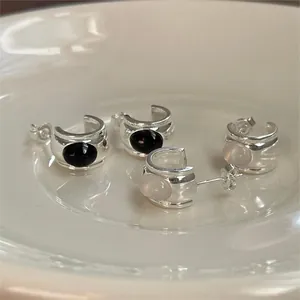 Detailed macro view of minimalist S925 silver stud earrings with black and pink gemstones