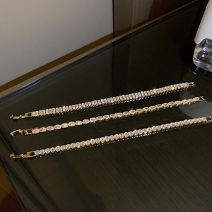 Detailed view of three gold bracelets with round, oval, and rectangular zircon stones