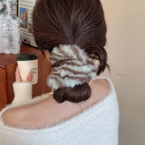 Primo piano di un elastico in peluche a righe marroni e bianche su uno chignon