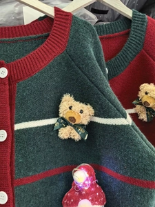 Detailed close-up of green Christmas cardigan with doll accessory and glowing lights