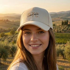 Beige cotton baseball cap with NYC embroidery worn by model in sunset landscape