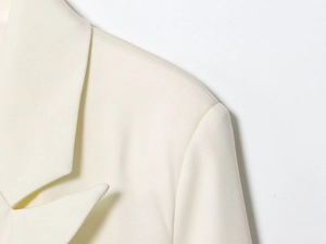 Detailed macro view of cream blazer lapel showing fine twill fabric texture and stitching