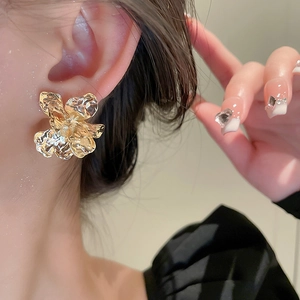 Close-up of golden irregular metallic flower earrings with textured finish on model