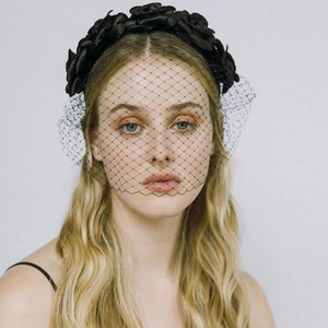Detail of vintage black camellia headband with elegant birdcage veil for parties