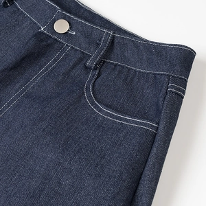 Gros plan d'un jean bleu foncé avec bouton métallique argenté et coutures blanches nettes