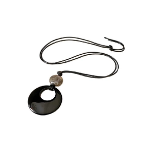 Minimalist geometric necklace with black open circle pendant and brown agate bead on white base