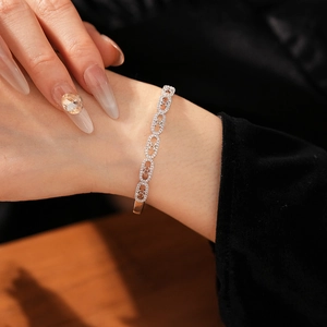 Close-up of a gold-plated oval bangle featuring sparkling cubic zirconia and a C-clasp