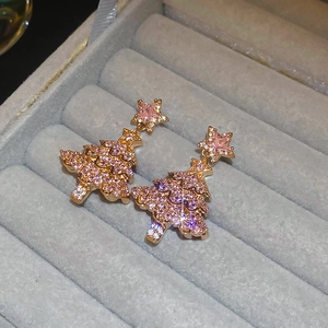 Golden Christmas tree earrings with pink gems and stars on a gray velvet jewelry box