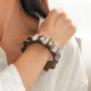 Detail shot of vintage amber acrylic bangle with wavy edges on model's wrist