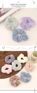 Dettaglio di morbidi elastici per capelli in peluche dai colori pastello su vassoio di legno