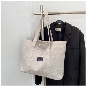Close-up of beige canvas tote bag showing coarse texture and fashion brand patch