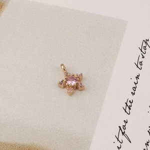 Detail of pink zircon star pendant with rose gold plating on vintage paper background