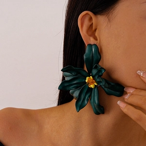 Detailed close-up of oversized matte dark green acrylic flower earrings with yellow beads