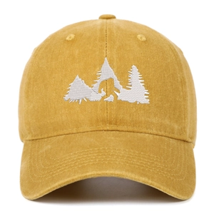 Dettaglio del cappellino vintage in cotone giallo senape con ricamo bianco Bigfoot e pini