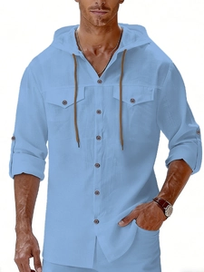 Detail of light blue linen hoodie shirt with buttoned pockets and rolled sleeves