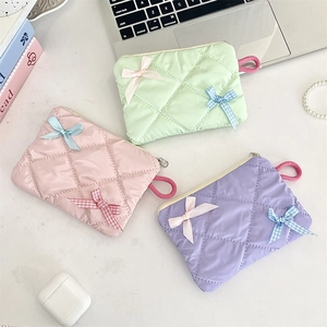 Three quilted pouch organizers in green, pink, and purple with decorative bow details
