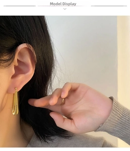 Detail of gold teardrop earrings with fine horizontal texture on female model