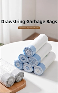 Close-up of white drawstring trash bags in rolls with blue pull ties on a wooden tray