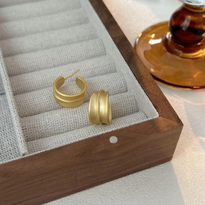 Minimalist matte gold half-hoop earrings displayed on a premium wood jewelry organizer