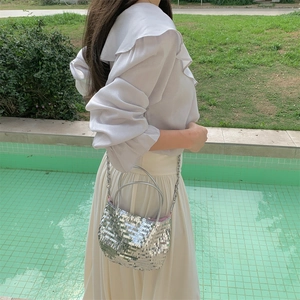 Detail of silver sequin tote bag with metal chain strap and pink lining in sunlight