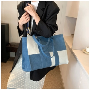 Detail of canvas and denim patchwork tote bag with adjustable shoulder strap and gold hardware