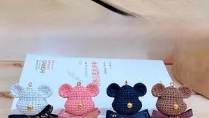 Detail of colorful hand-crocheted bear keychains with ribbon bows on wooden desk