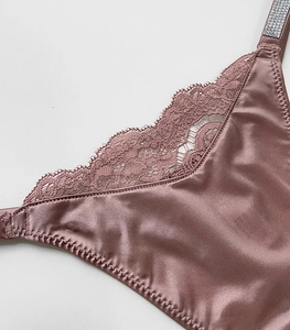 Close-up of pink satin panties with intricate lace trim and sparkling rhinestone straps