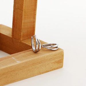 Close-up of minimalist S925 sterling silver U-shaped hoop earrings on a wooden display