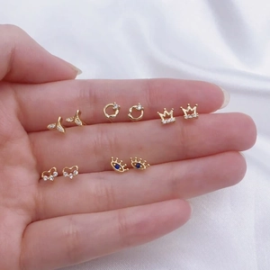 Golden stud earrings set with crown and heart designs on white fabric background