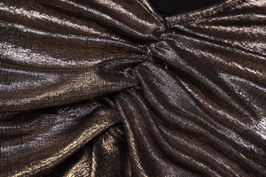Gros plan sur un tissu en maille pailleté bronze avec d'élégants détails plissés