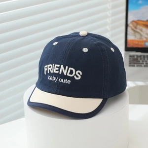 Close-up of baby baseball cap featuring navy blue cotton and white Friends embroidery