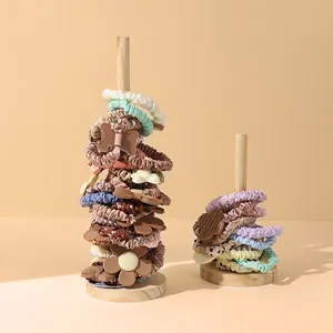 Wooden display stand featuring various scrunchies in solid colors and floral patterns