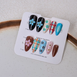 Detail of semi-handmade press-on nails with 3D flower carvings and plaid patterns