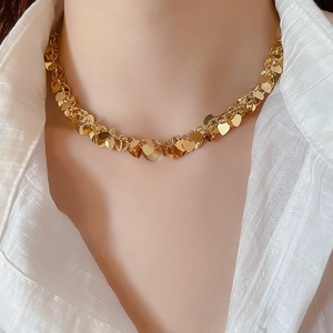 Dettaglio di una collana con frange e paillettes dorate a forma di cuore sul collo