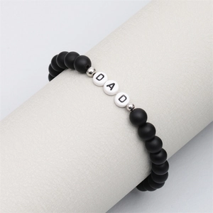 Detail of matte black beads bracelet with silver spacers and white DAD letter beads