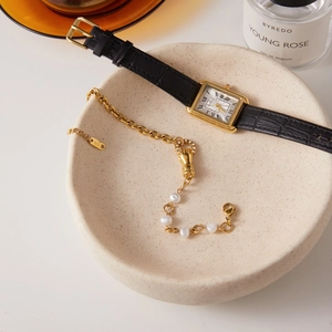 Détail d'un bracelet en or K18 avec perles et montre vintage en cuir doré