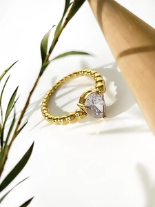Detail of 18K gold pear-cut zircon ring with elegant bubble band design on wood texture