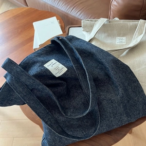 Détail macro de sacs fourre-tout en denim bleu et toile écrue posés sur une table en bois