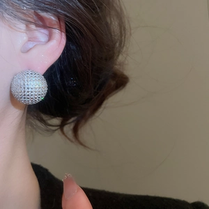Close-up of model wearing large sparkling silver zircon sphere stud earrings on the ear