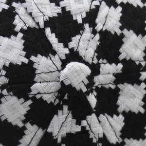 Macro shot of black and white houndstooth fabric and top button on baseball cap
