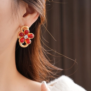 Close-up of vintage gold flower earrings with red gems and crystal on female model