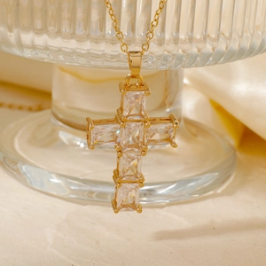 Macro detail of gold cross pendant with cubic zirconia on elegant beige satin backdrop
