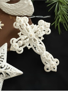 Detail view of glittery white cross and star ornaments hanging with silver strings