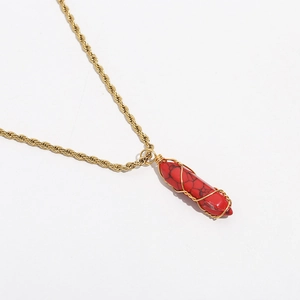 Macro shot of red hexagonal stone pendant with gold wire wrapping and twisted chain